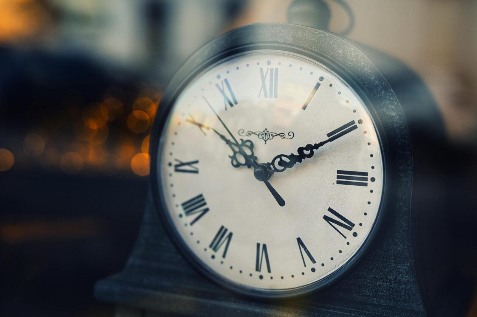Close-up of a vintage clock with Roman numerals, softly lit background.