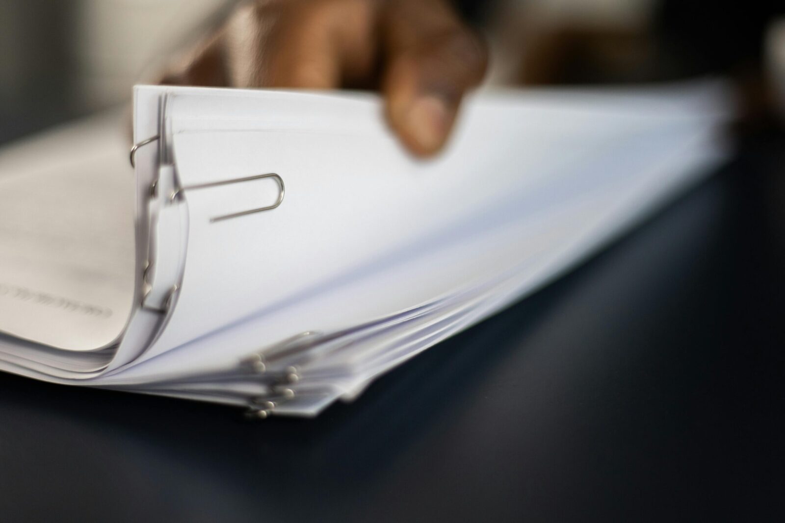 Detailed image of paper stacks held together by paperclips, showcasing organizational tools.