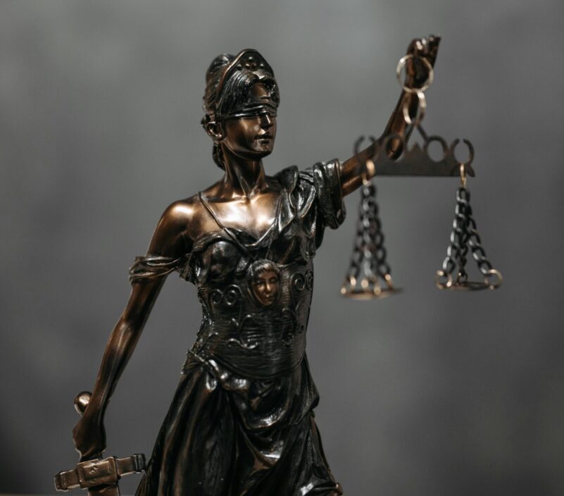 Close-up of a bronze Lady Justice statue holding scales, symbolizing law and fairness.