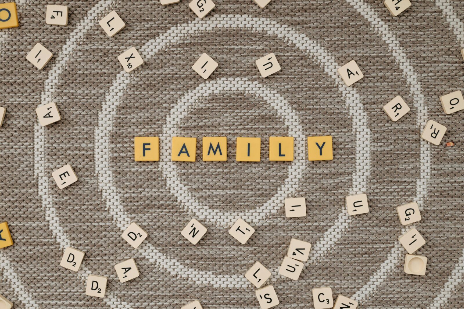 Scrabble tiles spelling 'family' on a textured brown surface, surrounded by scattered tiles.