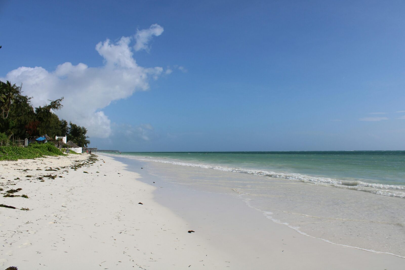 Idyllic white sand beach and azure ocean under clear skies in Zanzibar, Tanzania.
