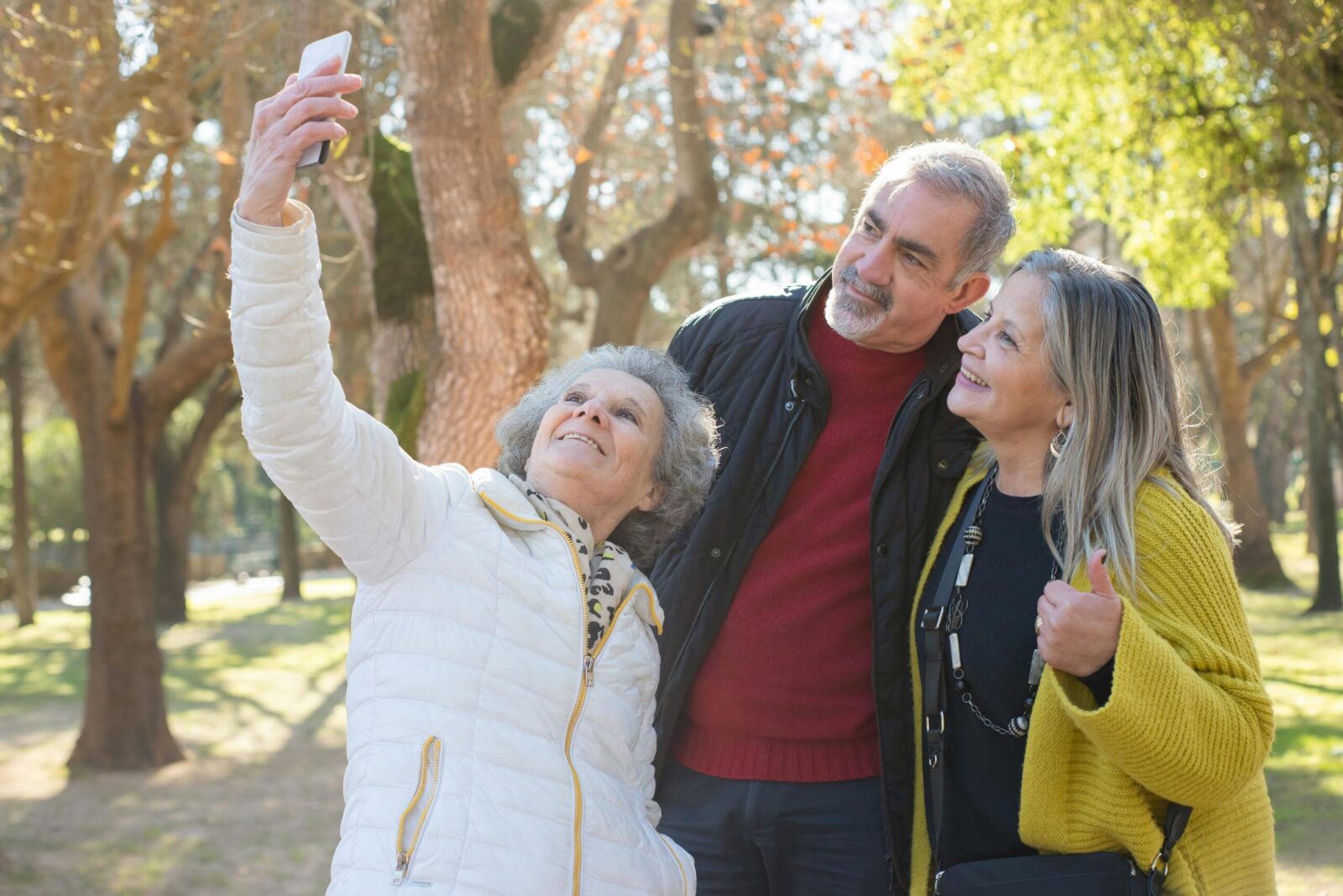 Group of cheerful seniors taking a selfie together outdoors, capturing a moment of joy.