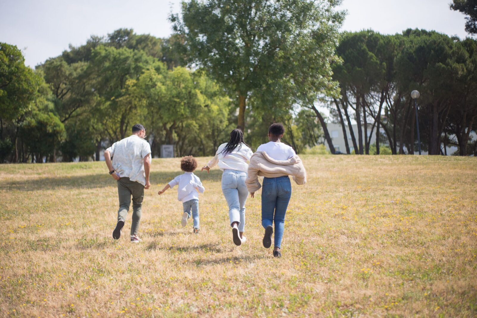 Cheerful family walking together in a sunny park surrounded by trees.