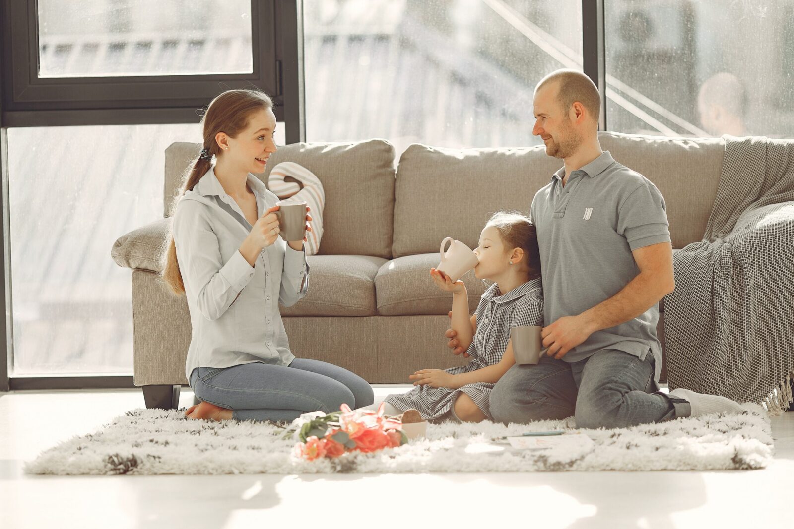 Cheerful family drinking tea in living room while having rest and laughing together during weekend while spending time and having fun