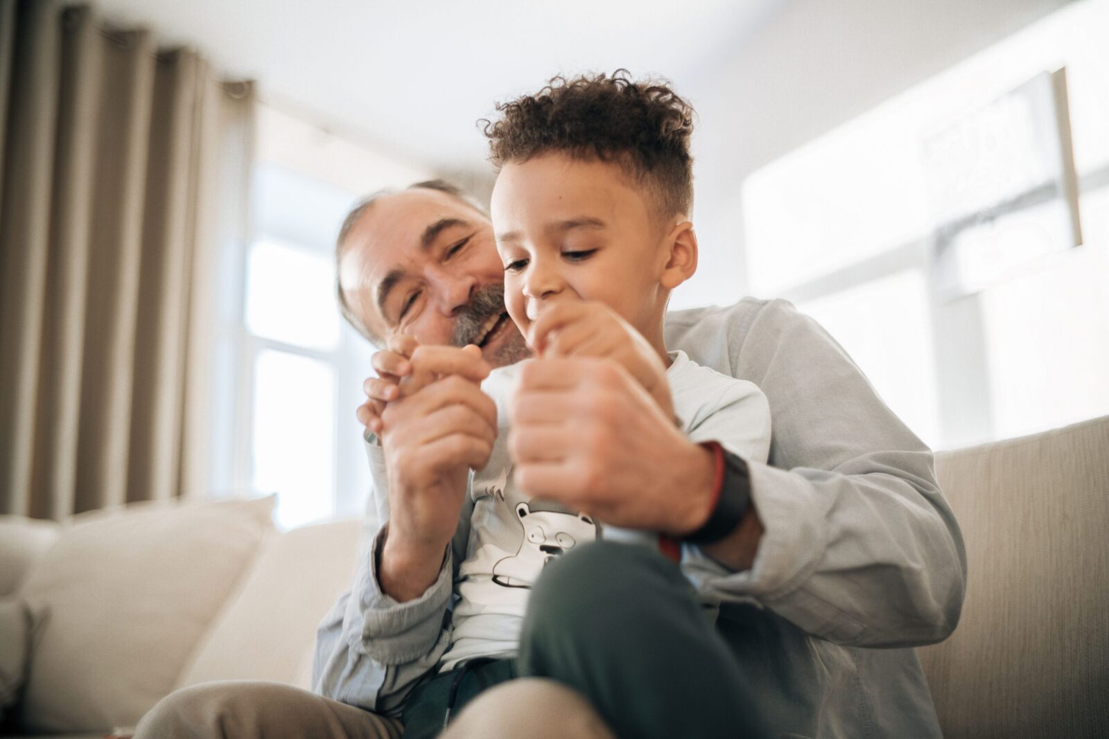 A grandfather and grandson enjoying playful quality time at home, showcasing family bonding.