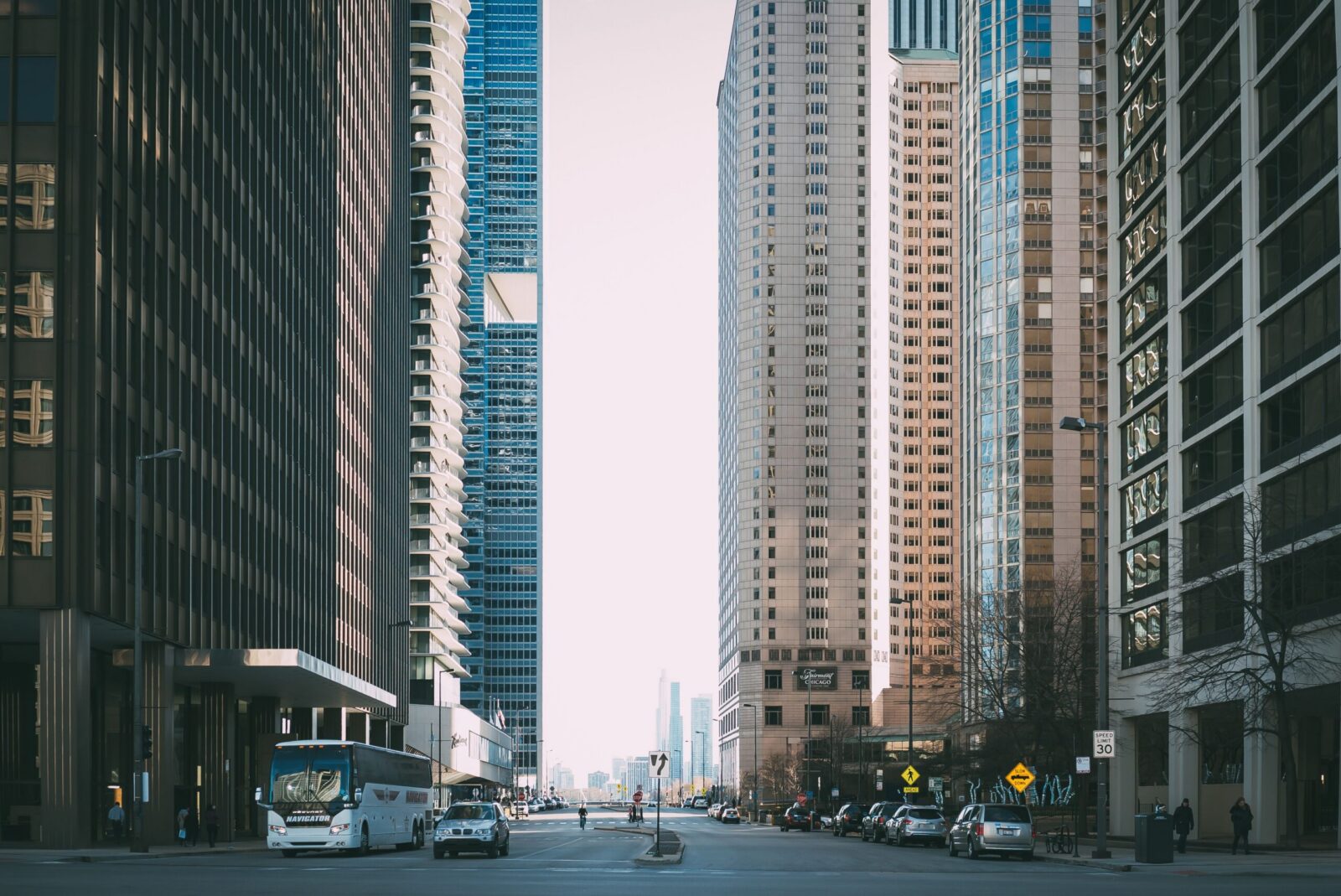 Vibrant city street scene with tall skyscrapers and city life full of cars and pedestrians.