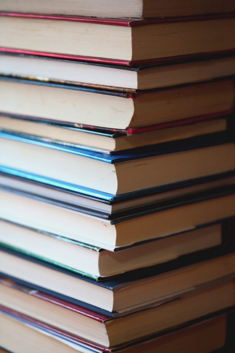 A close-up view of a tall stack of books arranged vertically indoors.