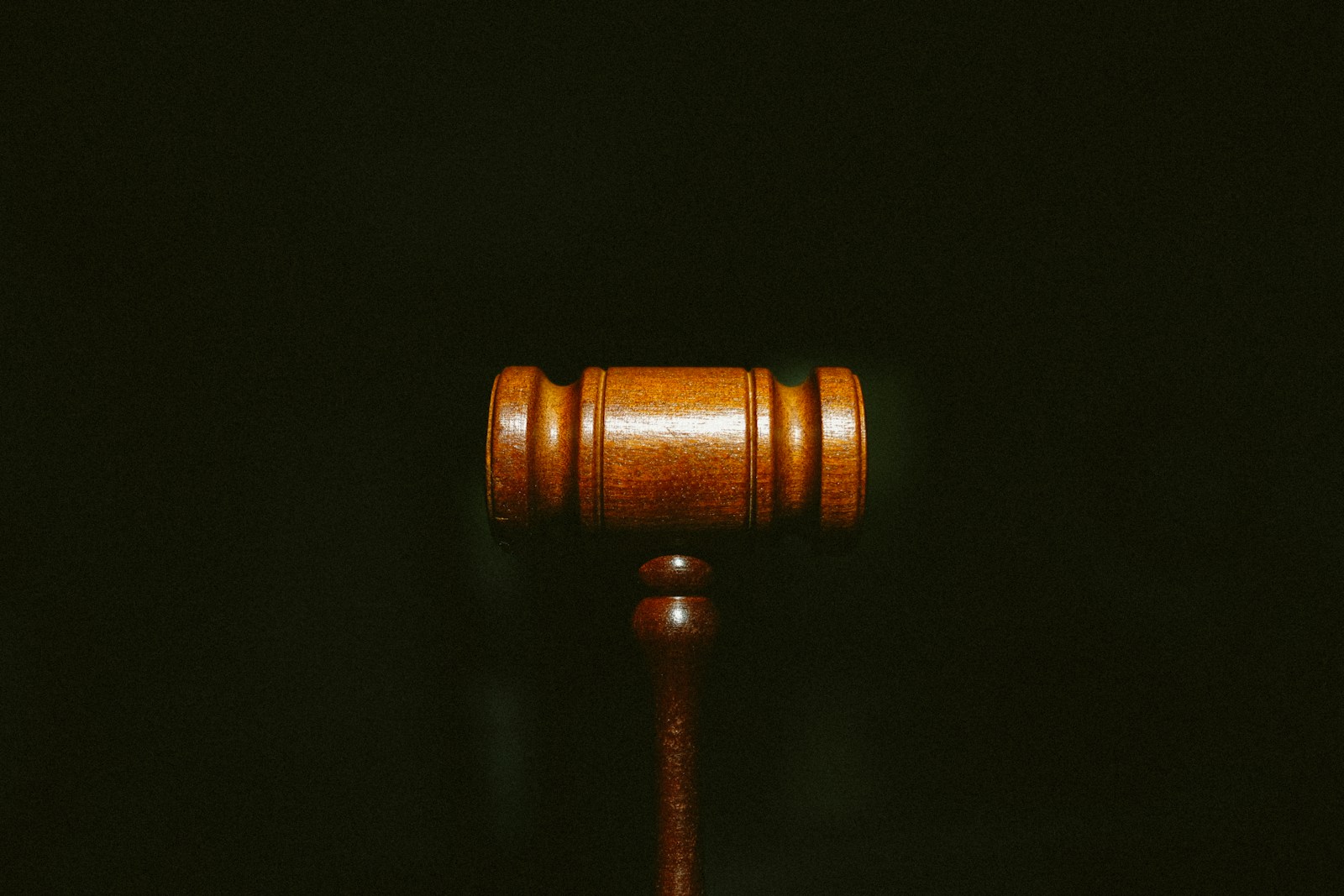 A polished wooden judge gavel centered against a dark background
